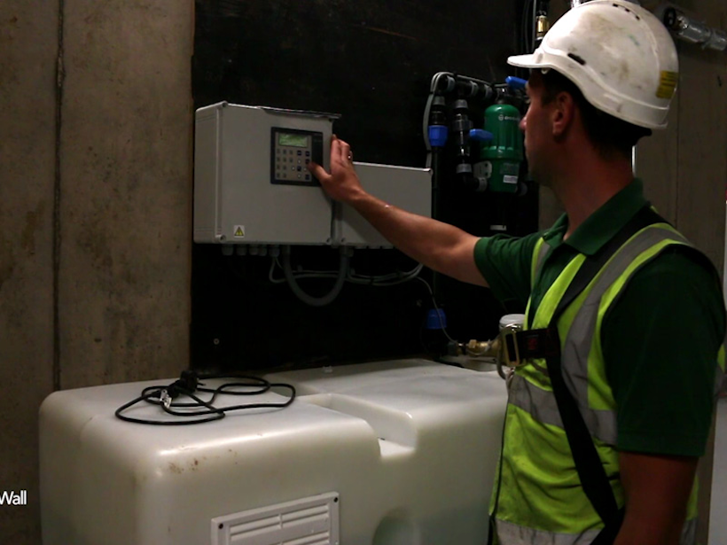 technician adjusting the irrigation system of a living wall in a plant room